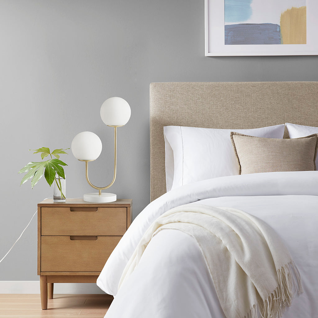 Table lamp in a modern bedroom with a bed, nightstand, and wall art.