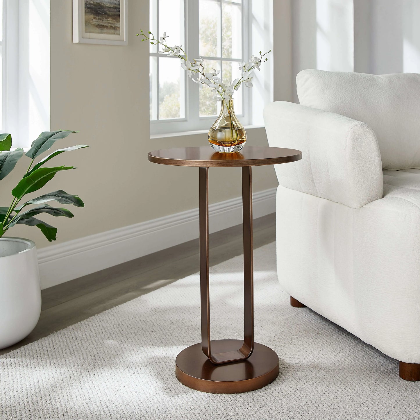 Antique bronze end table with a vase of flowers in a living room setting