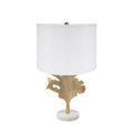 Table lamp with gold leaf design base and white shade on a white background