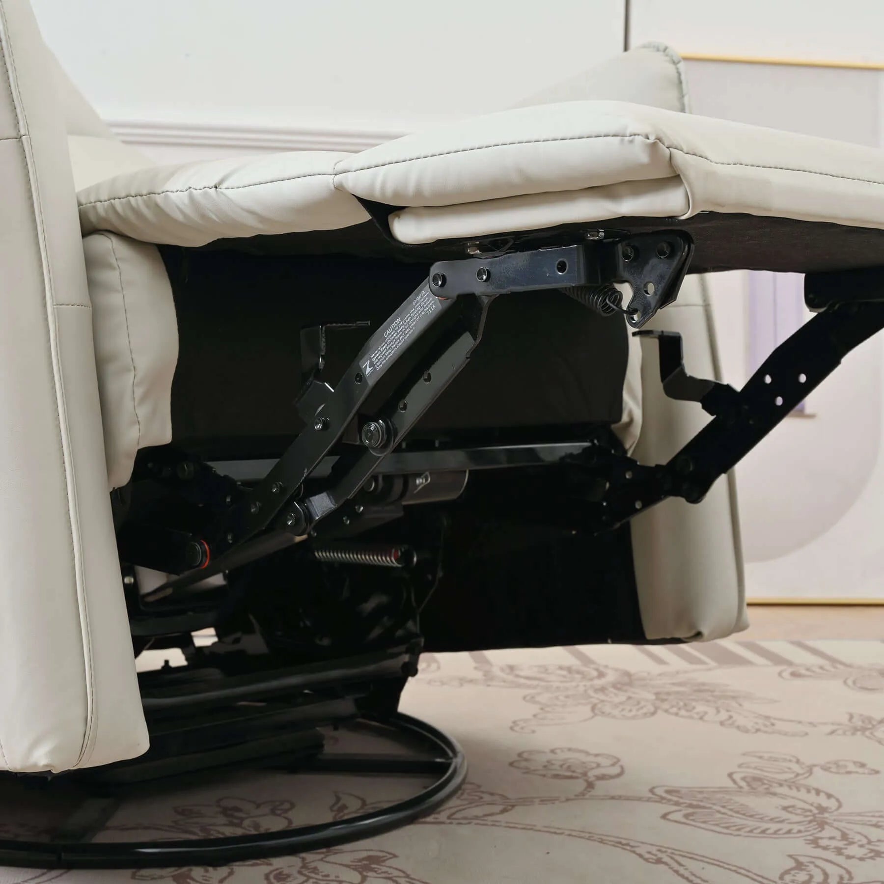 Close-up of a recliner chair mechanism with light gray cushions on a patterned carpet.