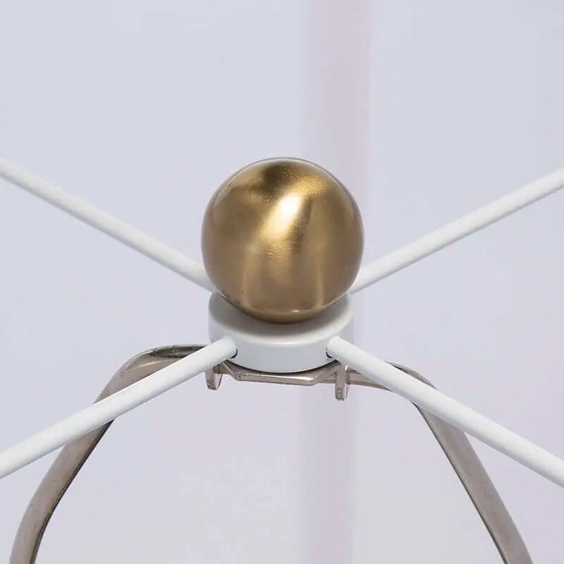 Close-up of a decorative item with a gold sphere and white spokes on a light gray background