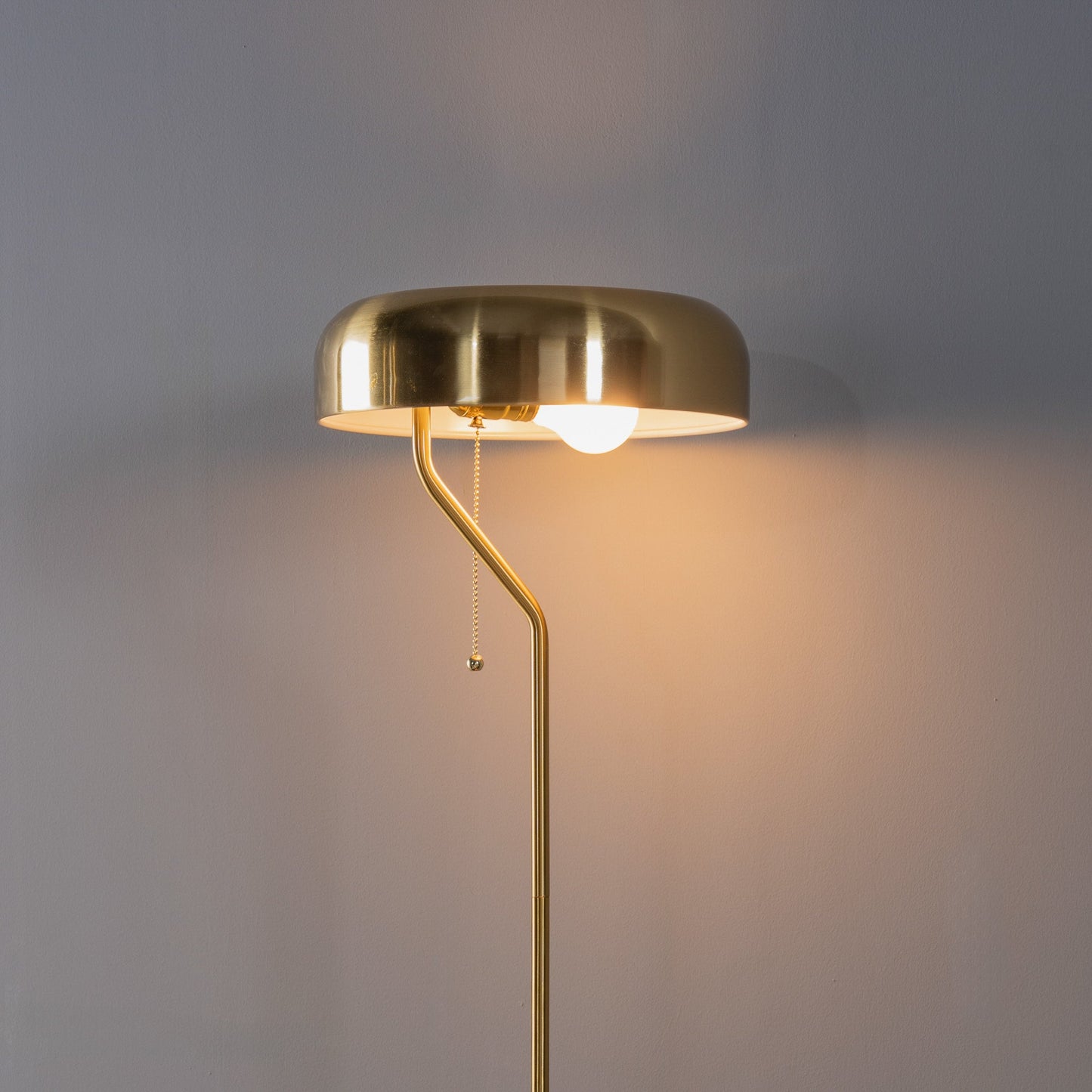 Gold floor lamp with a soft glow on a gray background