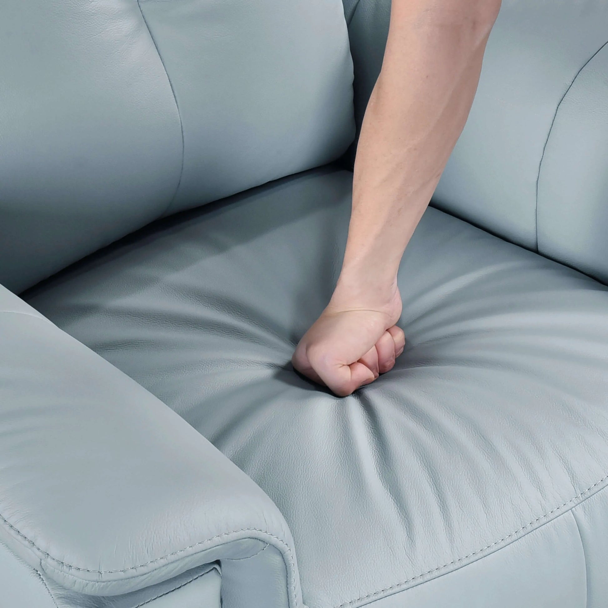Person's fist resting on a blue recliner chair seat cushion