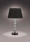 Table lamp with black shade and silver base on a dark background
