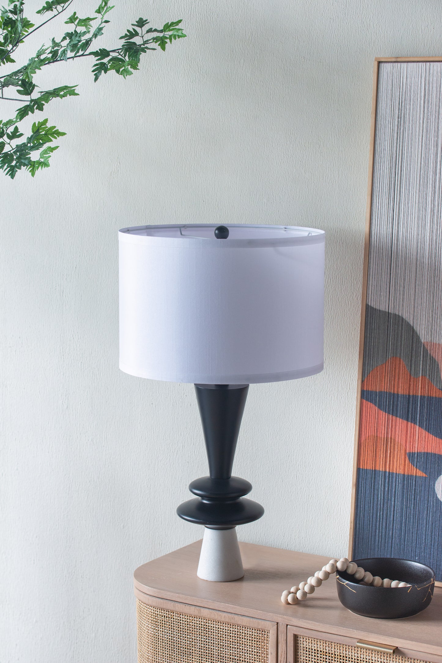 Table lamp with a white shade on a wooden side table against a light wall.