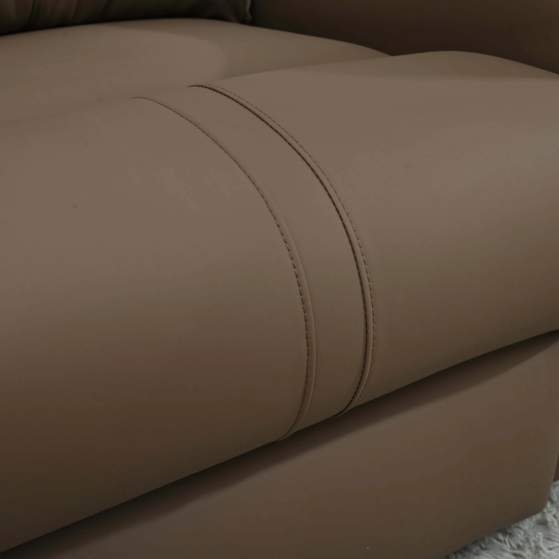 Close-up of a brown leather recliner chair with visible stitching.