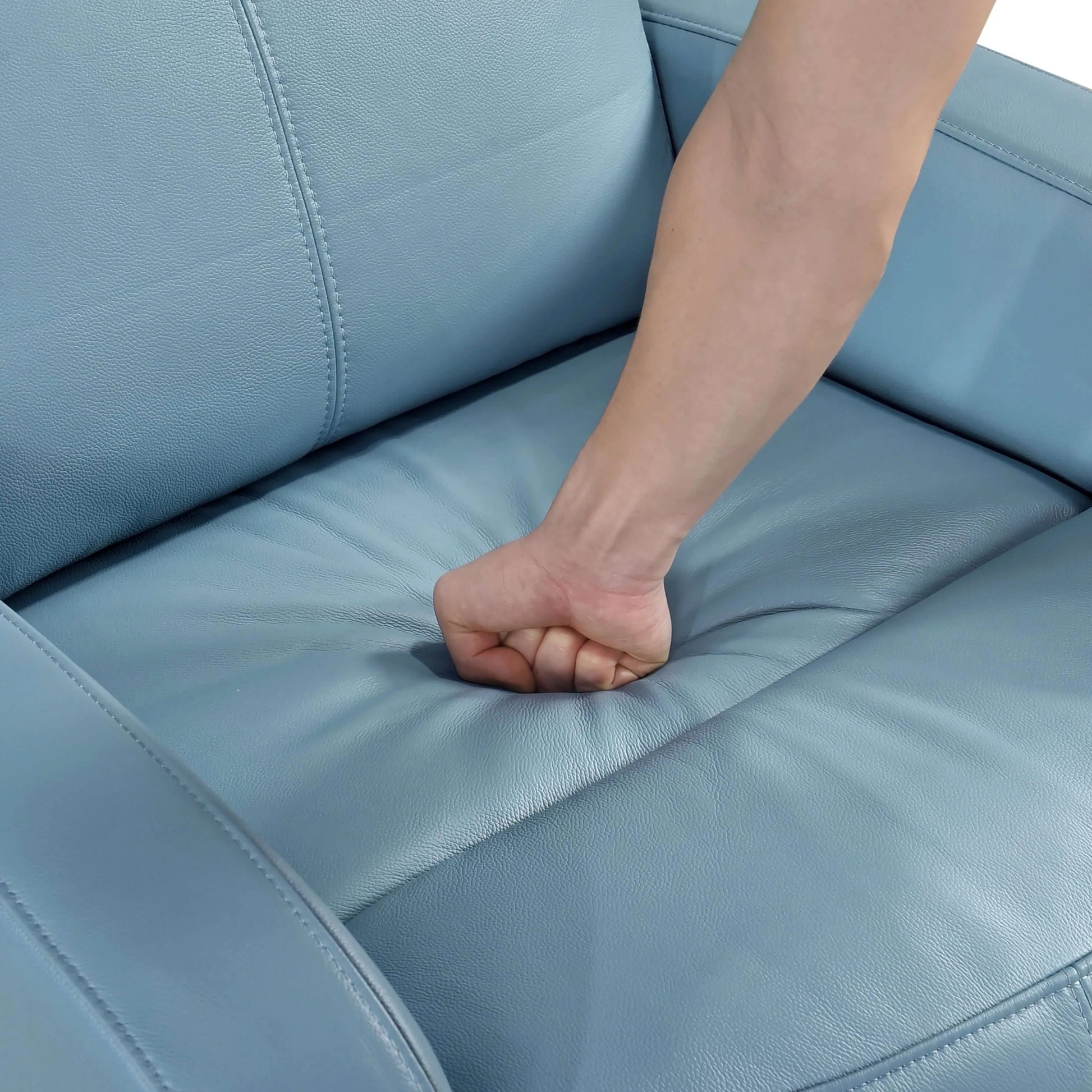 Hand pressing down on a blue recliner chair seat cushion