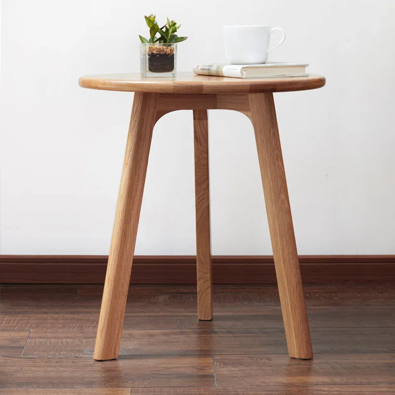 Wooden accent table with a plant and books on a white wall background