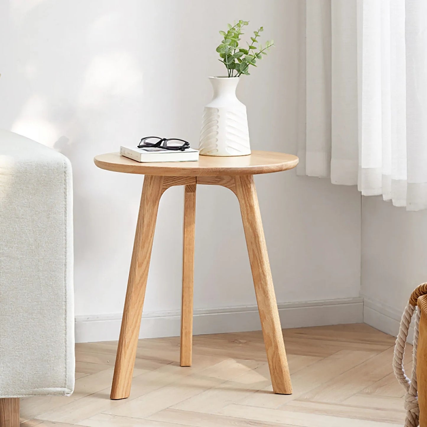 Wooden end table with a vase, books, and glasses in a room setting.