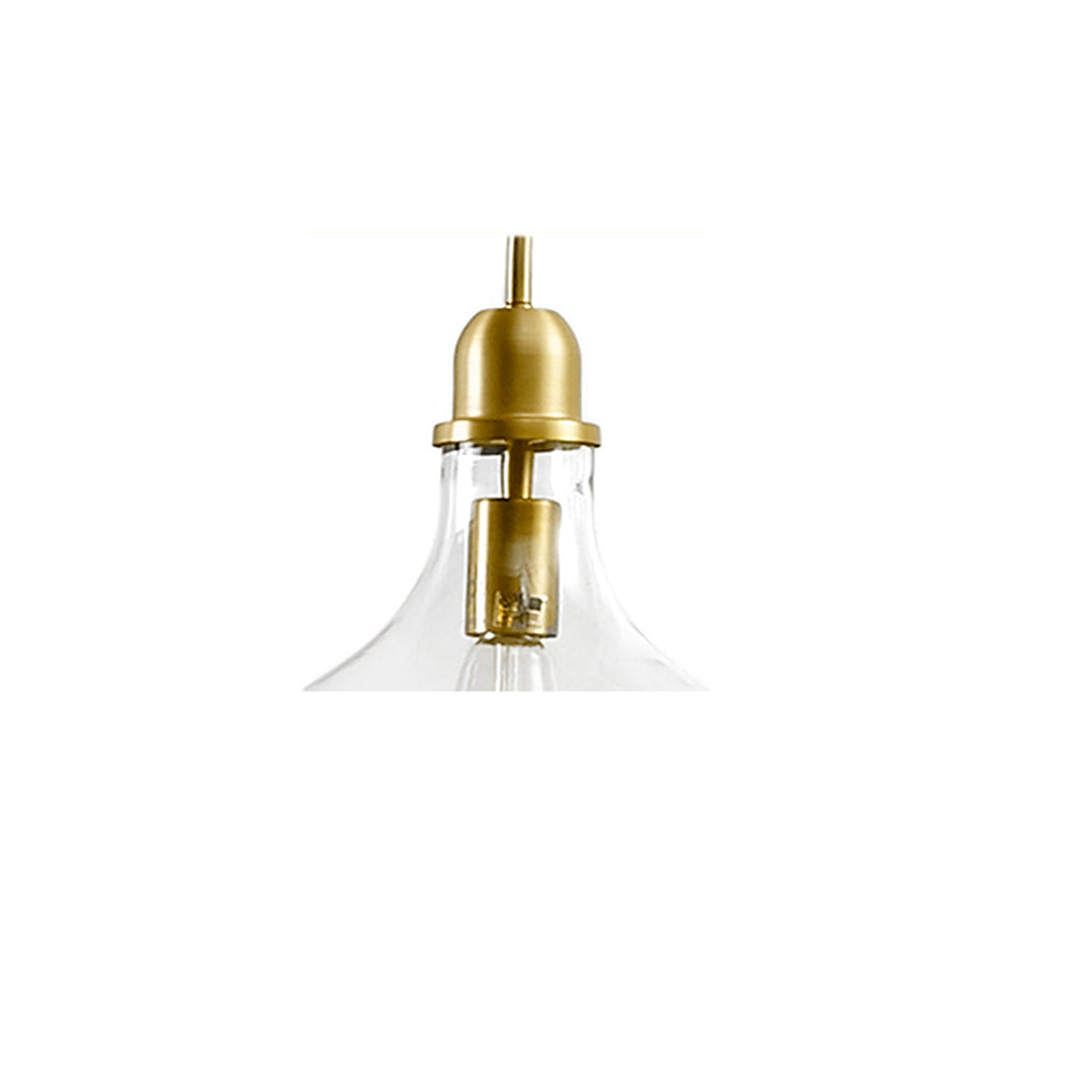 Clear glass pendant light with gold metal fixture on a white background