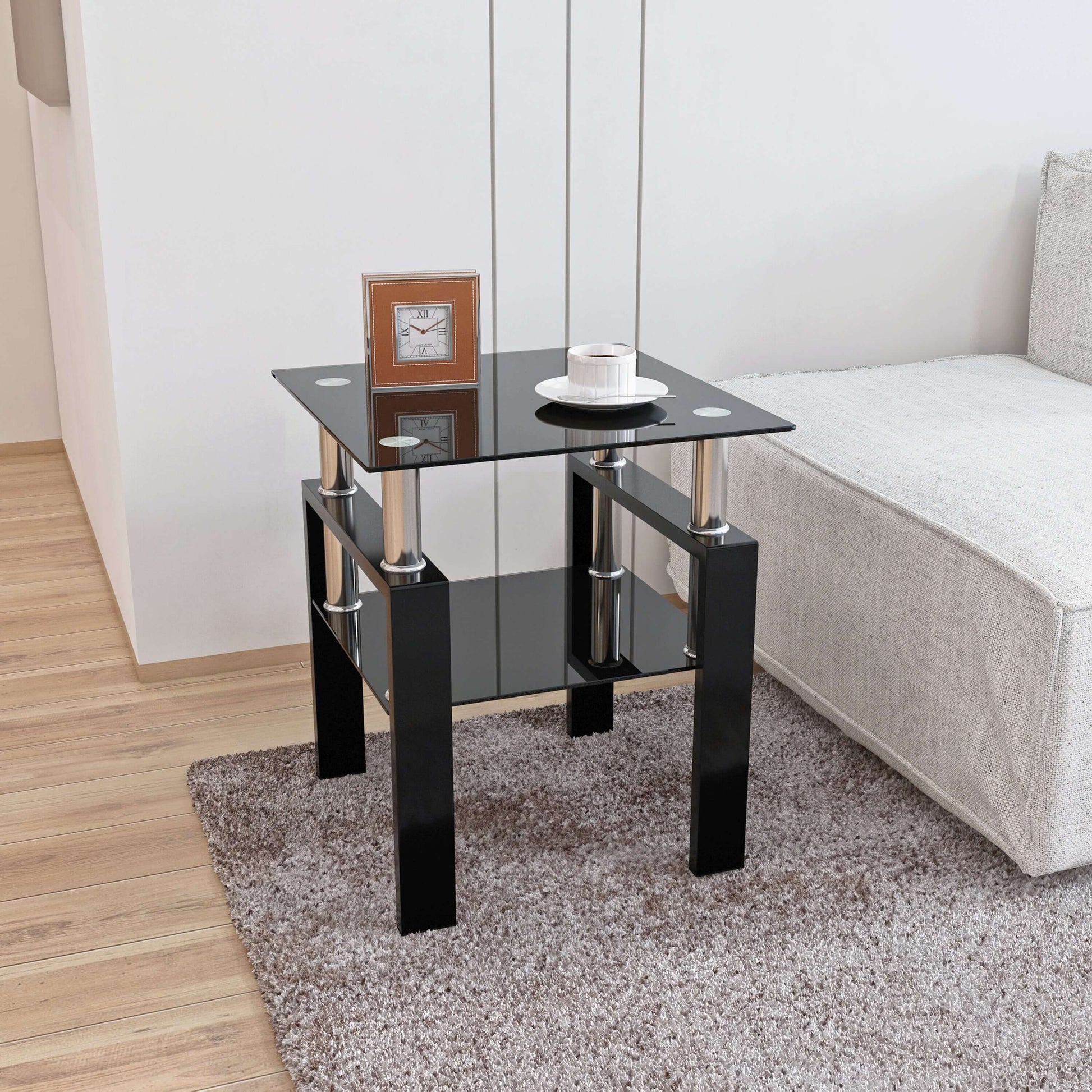 Black glass end table with a clock and small plate in a living room setting.