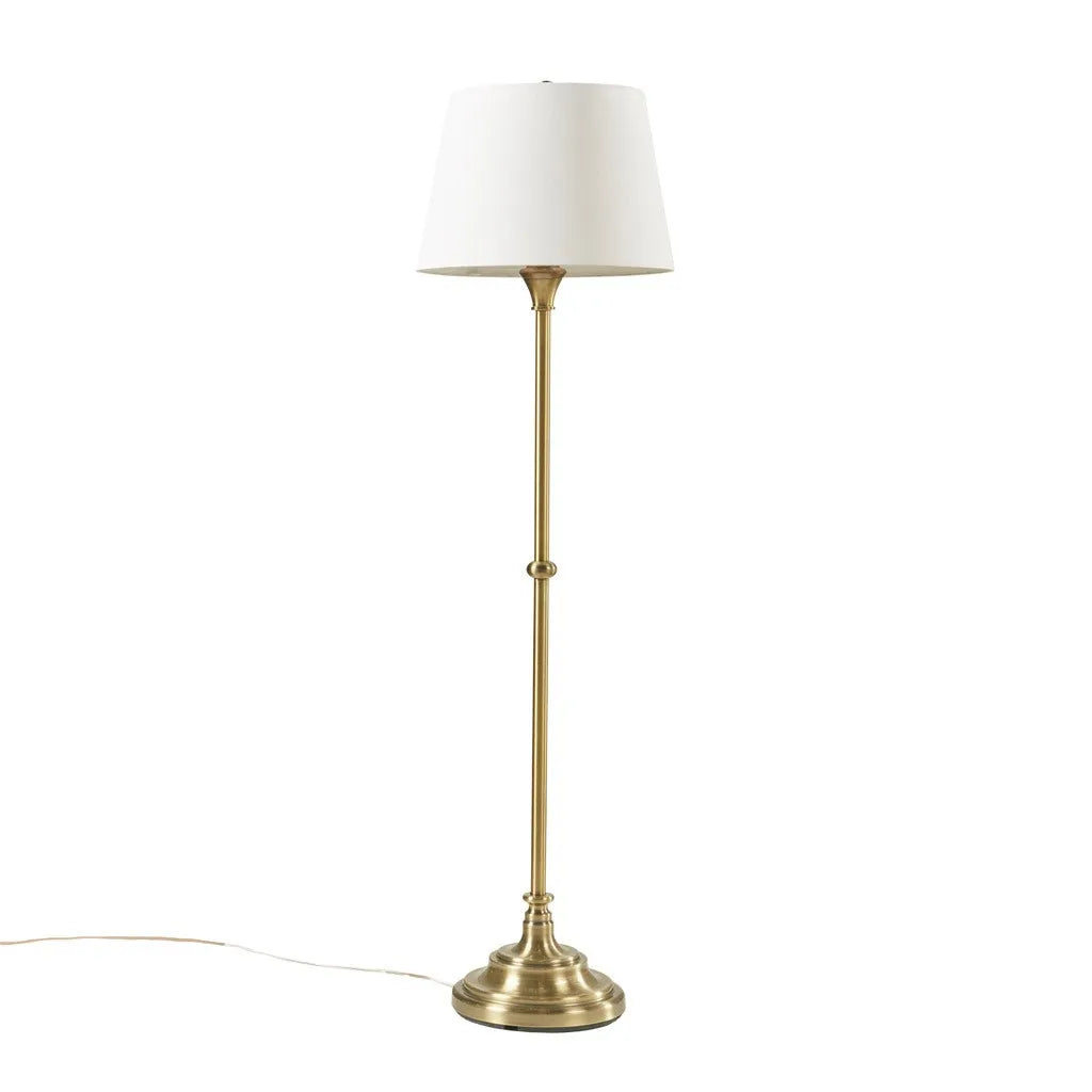 Floor lamp with brass base and white shade on a white background