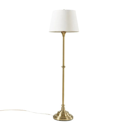 Floor lamp with brass base and white shade on a white background