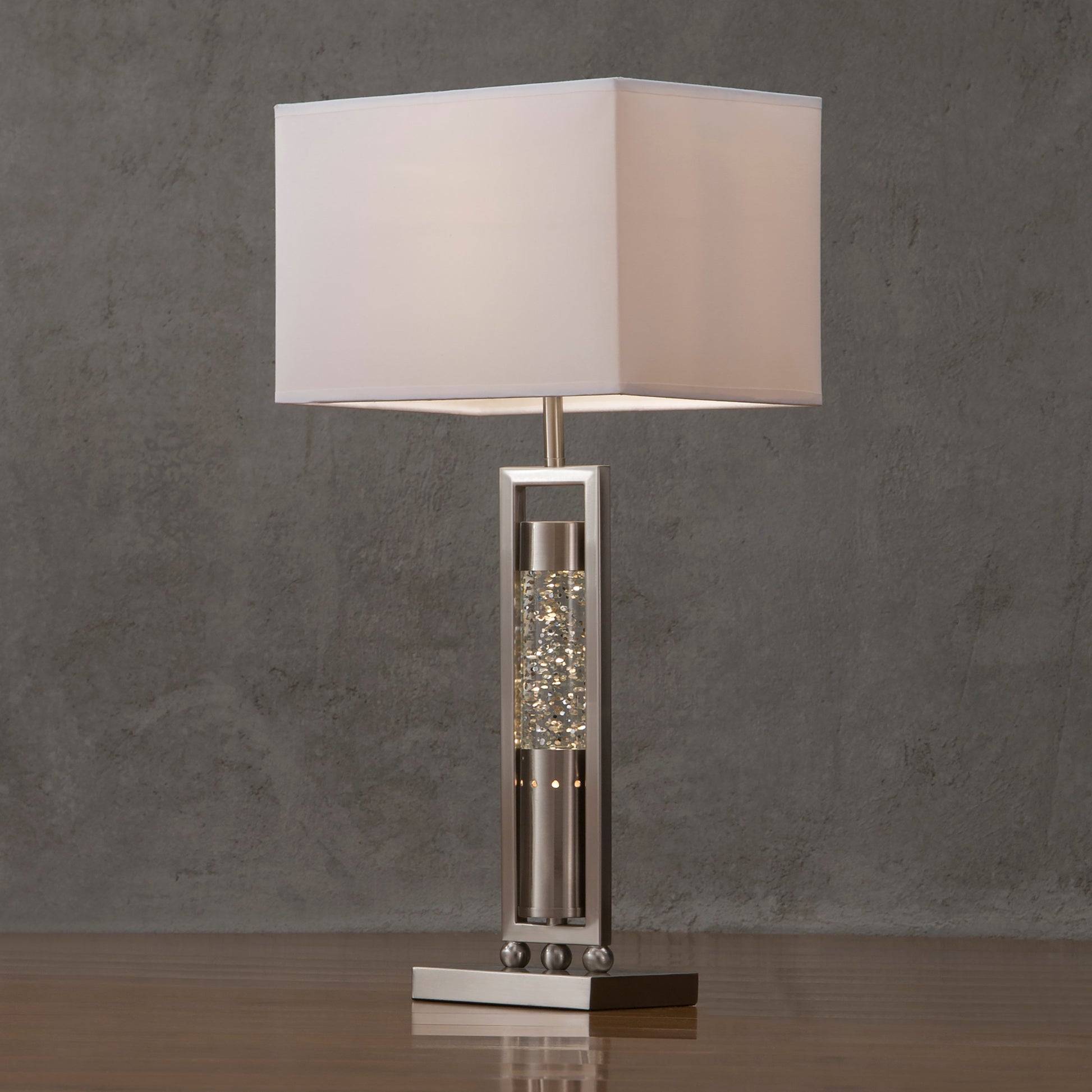 Table lamp with a decorative base on a wooden surface against a gray wall
