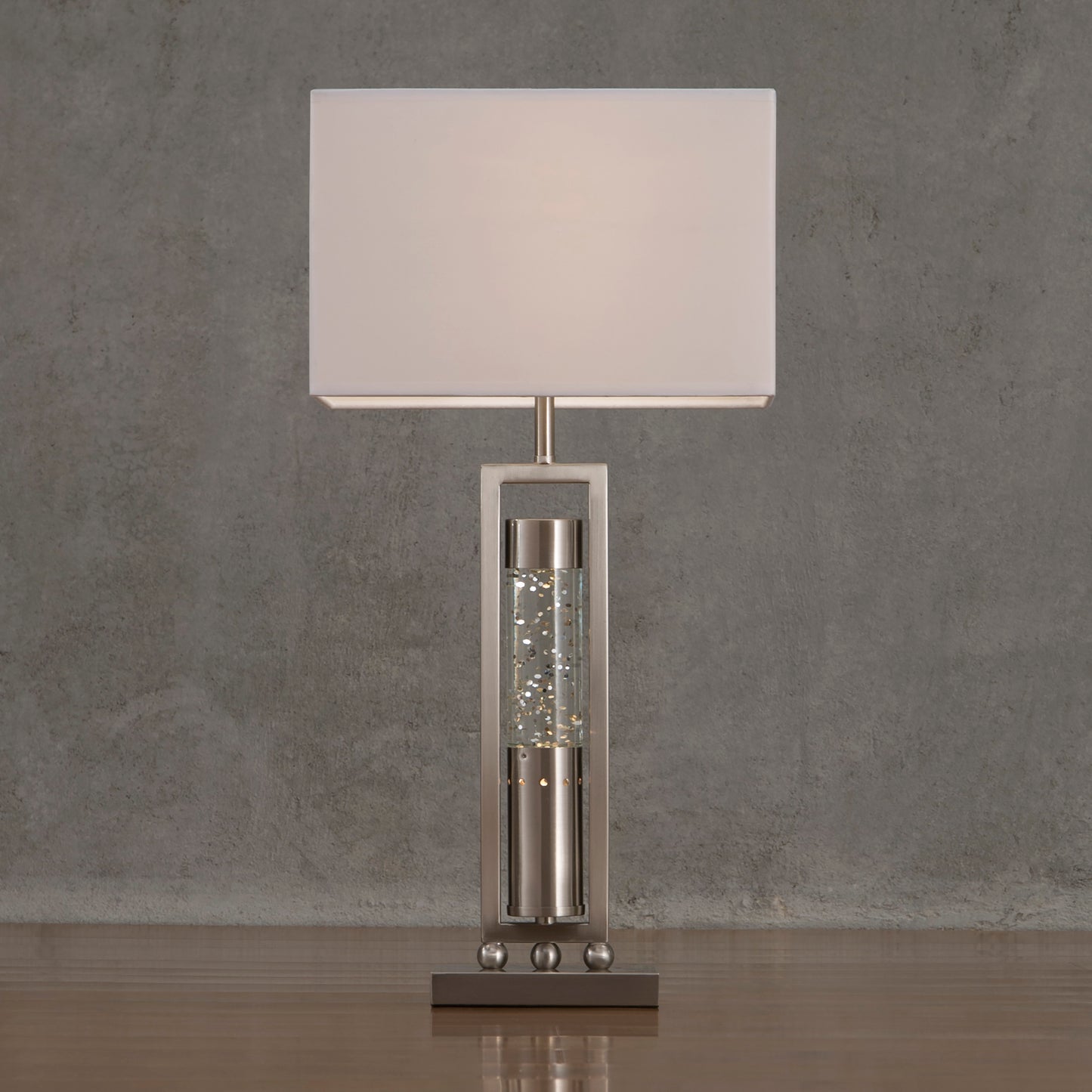 Table lamp with a white shade and decorative base on a gray surface.