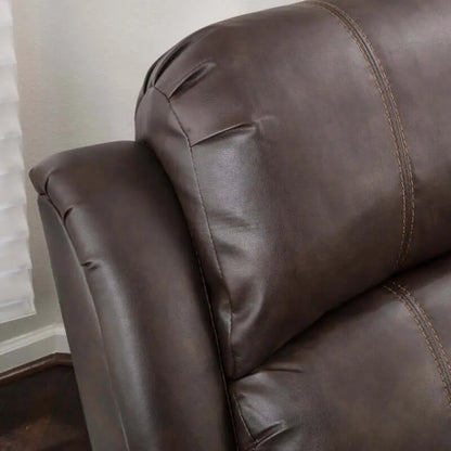 Close-up of a top cushion with visible stitching of a brown faux leather glider recliner.