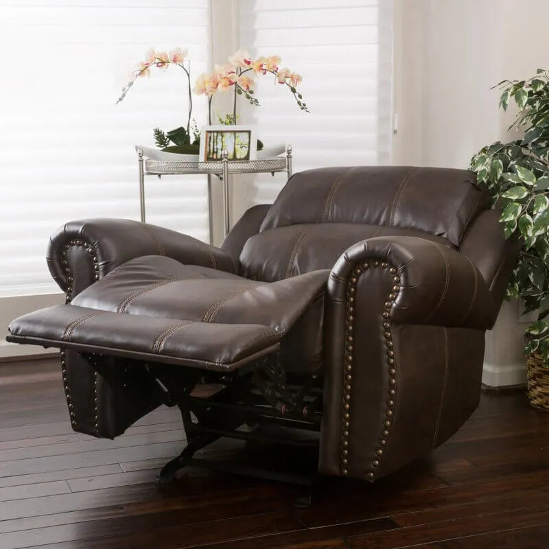 Brown faux leather glider recliner chair in a reclining position in a living room setting with plants and a small table.