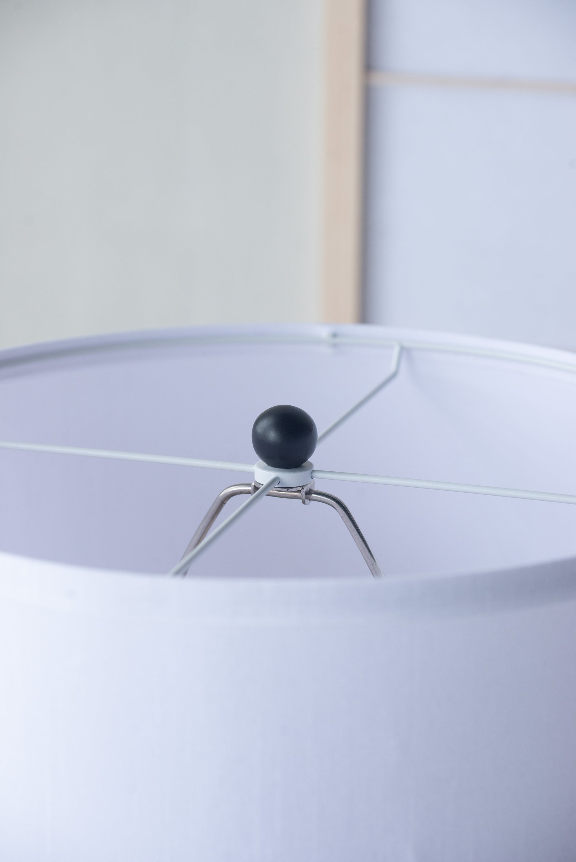 Close-up of a lampshade with a black finial and white background