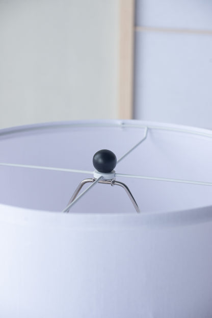 Close-up of a lampshade with a black finial and white background
