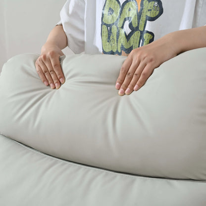 Person squeezing top cushion of a light gray recliner chair to demonstrate thickness. 