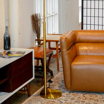 Living room with brown leather sofa, gold floor lamp, and wooden side table.