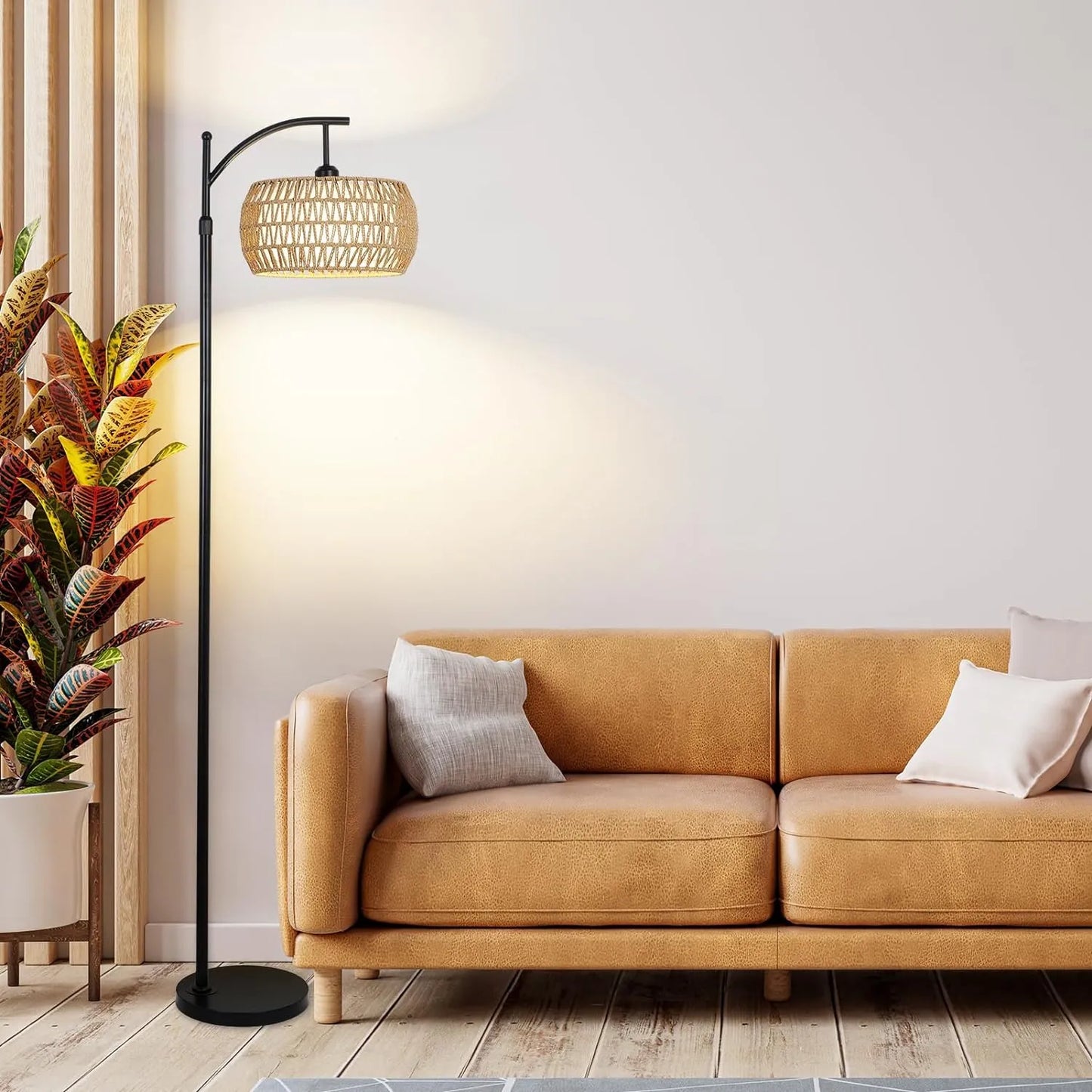 Tan sofa with decorative pillows in a living room setting with a floor lamp and plant.