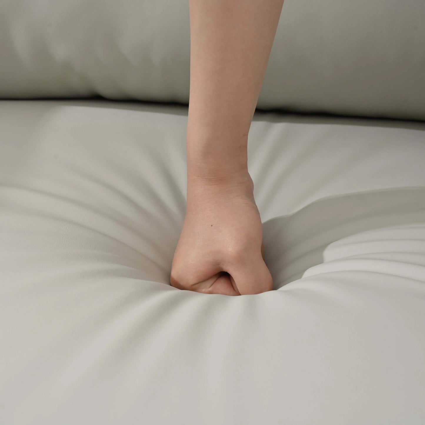 Hand resting on a light gray recliner chair seat cushion