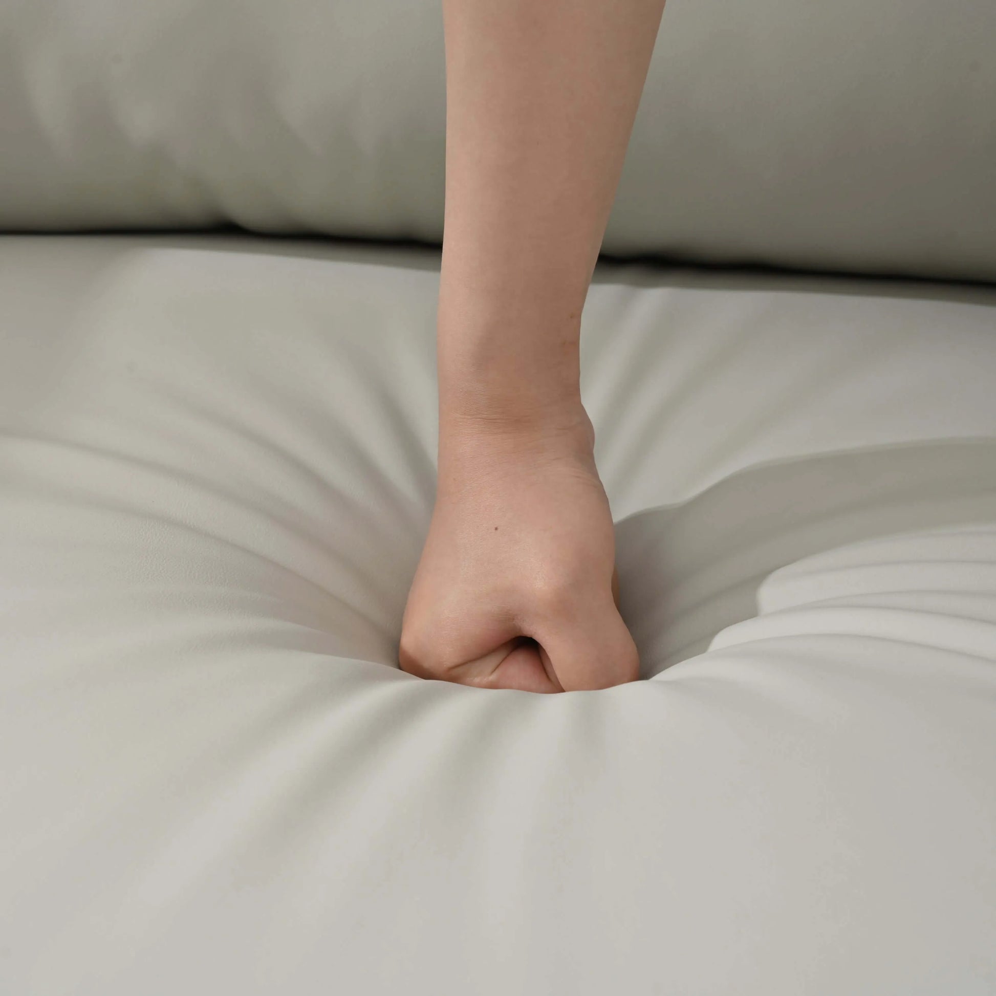 Hand resting on a light gray recliner chair seat cushion