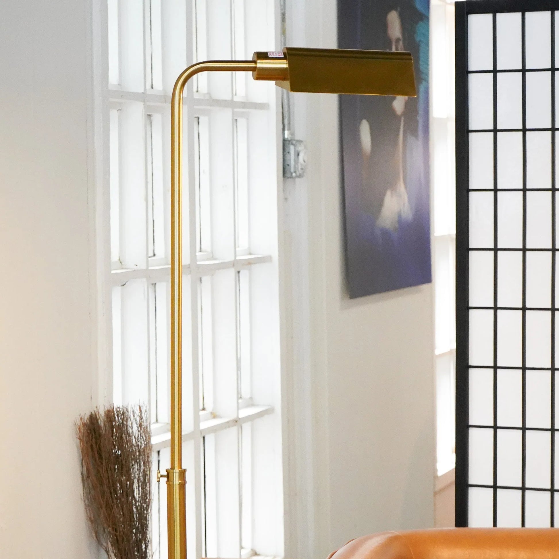 Brass floor lamp in a room with a window and decorative elements.