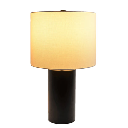 Illuminated table lamp with a drum shade and black base on a white background