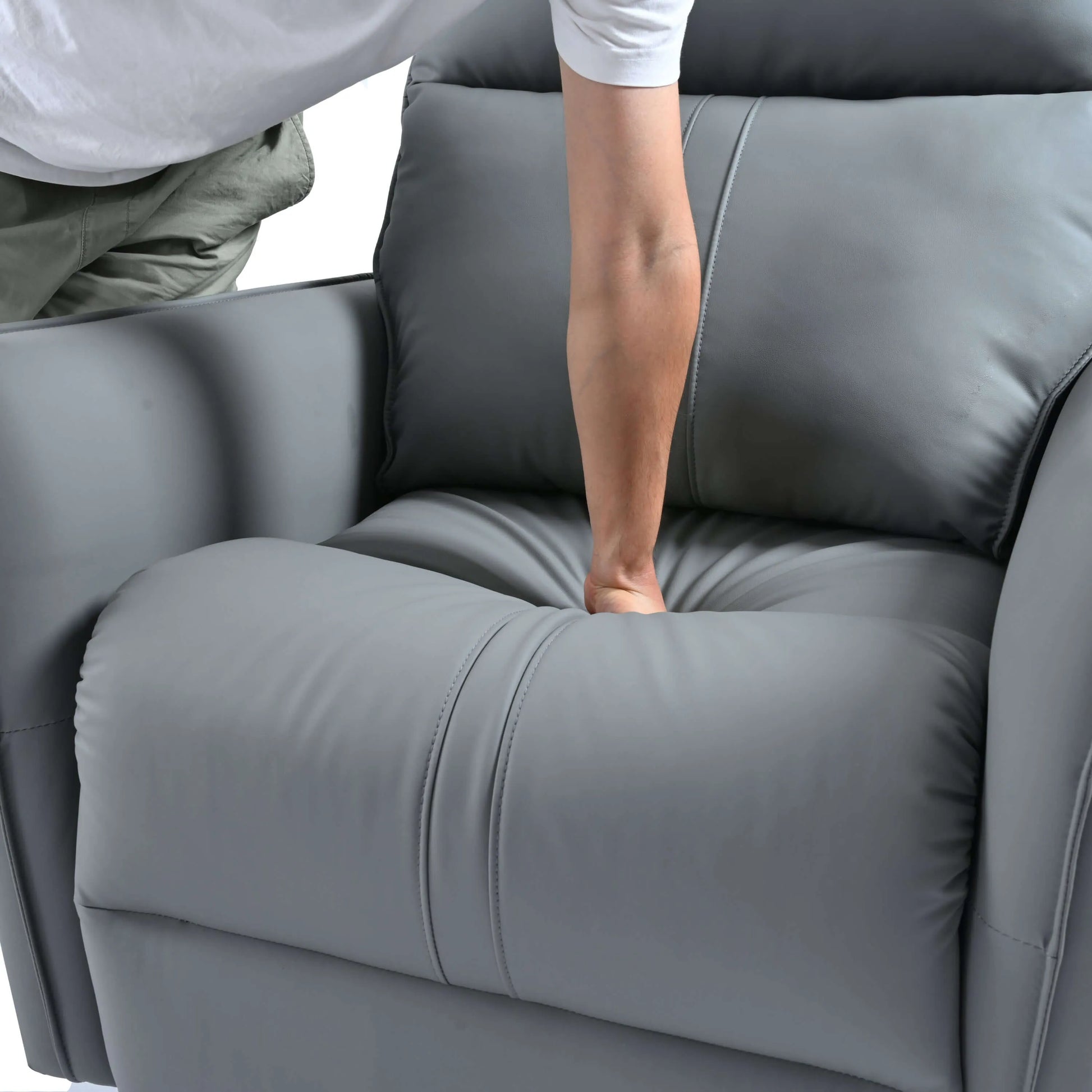 Person pushing down on a gray reclciner chair cushion with a blurred background
