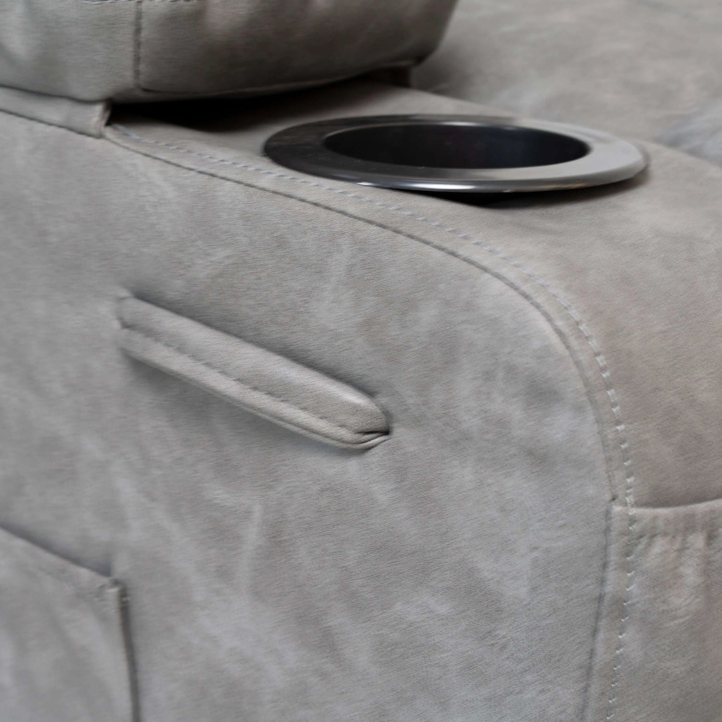 Close up of a gray faux leather power lift recliner chair cup holder and detailed stitching 