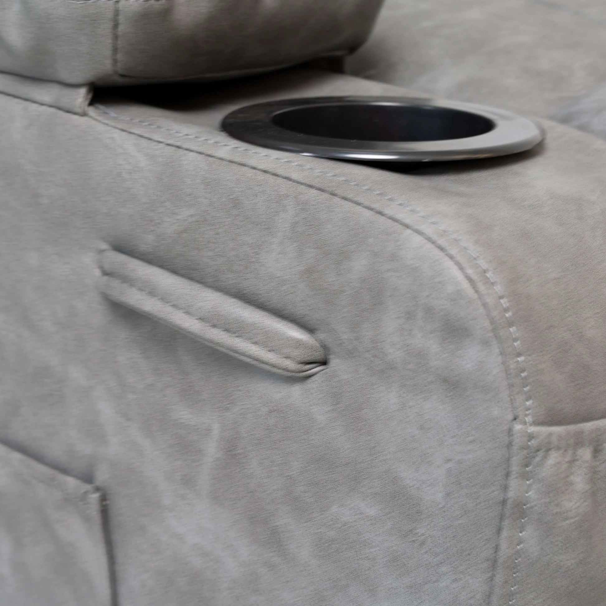 Close up of a gray faux leather power lift recliner chair cup holder and detailed stitching 