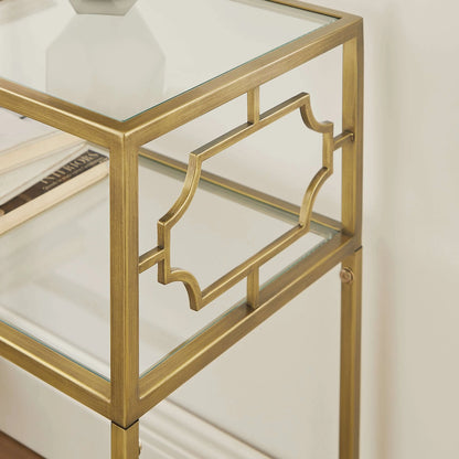 Gold-framed glass side table with 2 shelves and a white vase on a neutral background