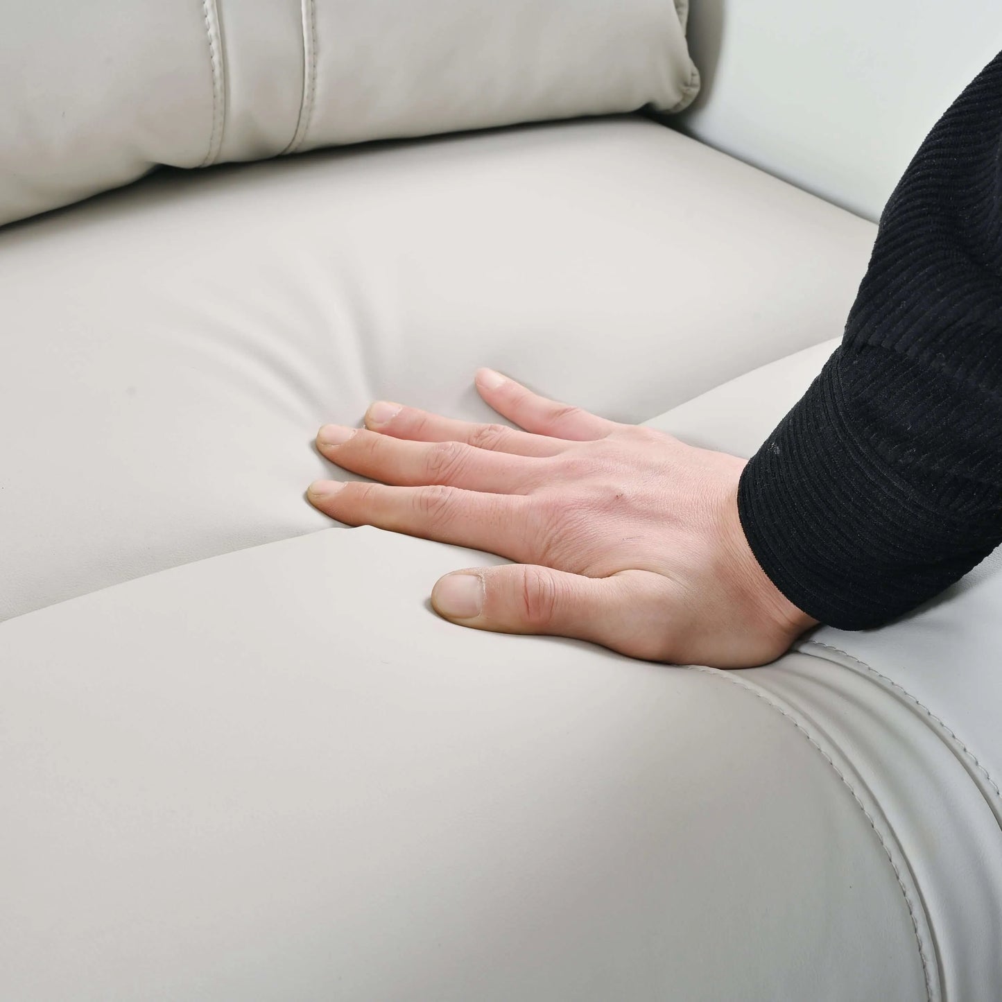Hand resting on a light gray recliner chair cushion