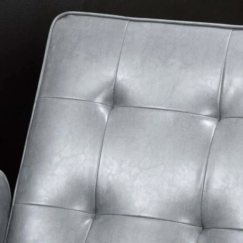 Close-up of a tufted gray leather recliner chair cushion with a dark background