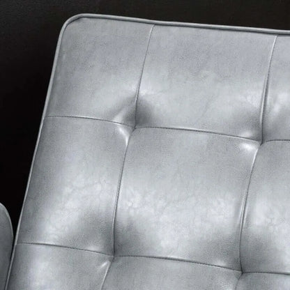 Close-up of a tufted gray leather recliner chair cushion with a dark background