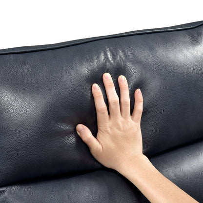 Hand touching a blue leather recliner chair top cushion on a white background
