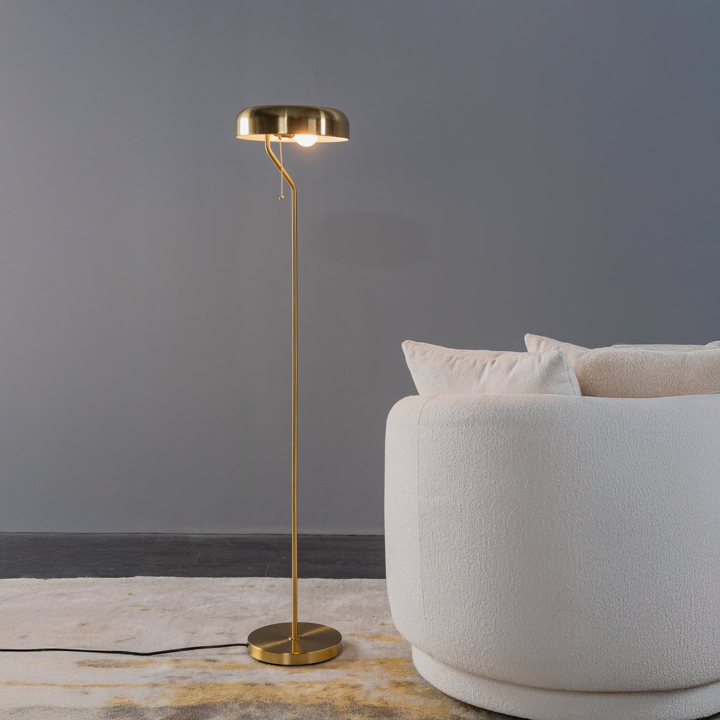 Gold floor lamp next to a white chair against a gray wall