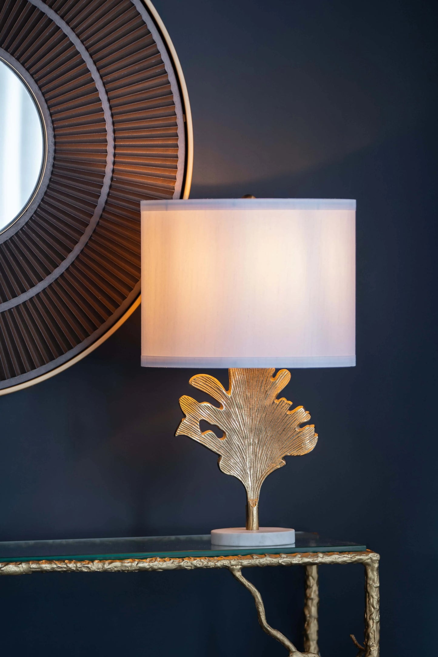 Decorative table lamp with gold leaf design on a dark wall background