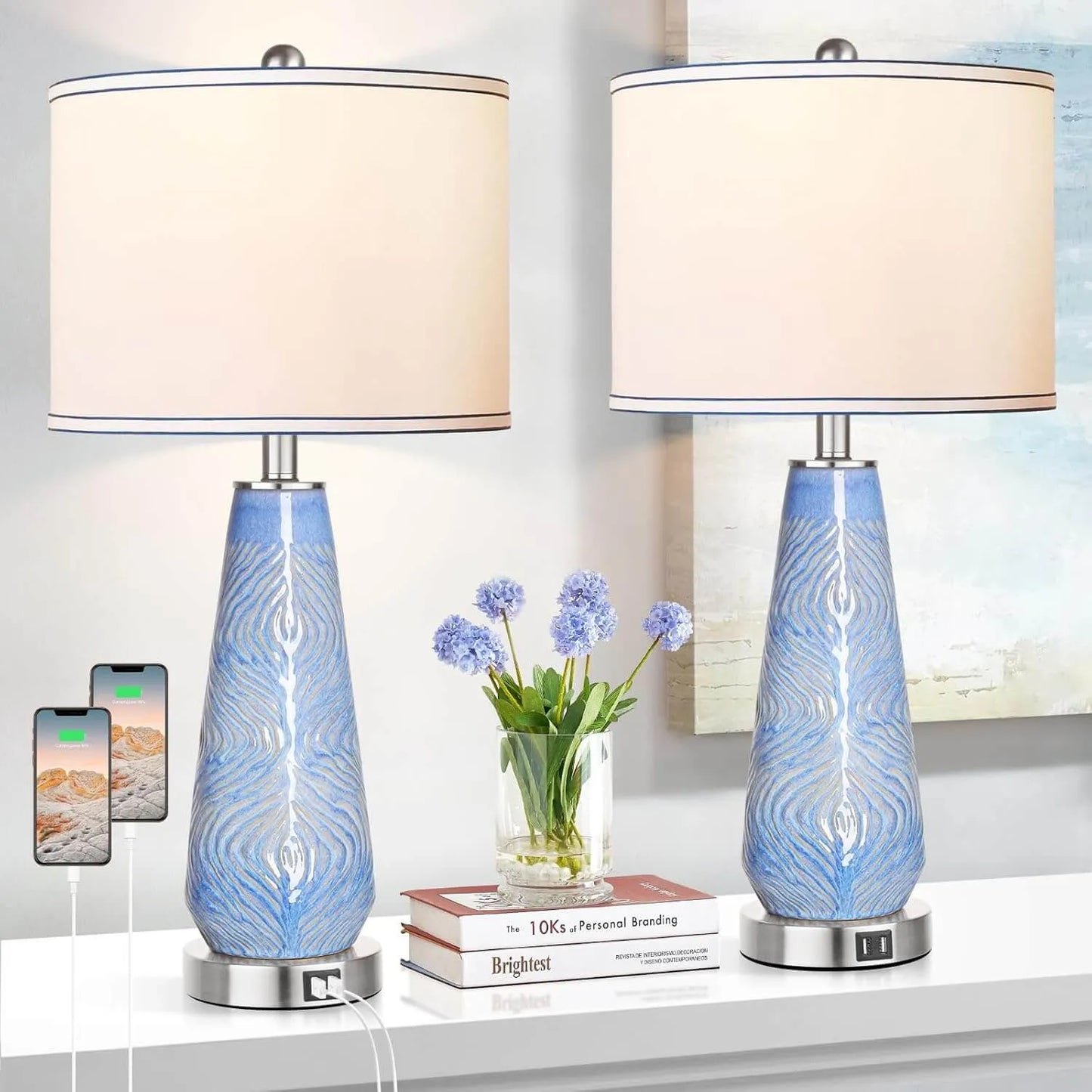 Two blue glass table lamps with white lampshades on a shelf.
