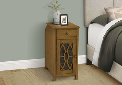 Wooden end table with decorative items next to a bed in a bedroom setting.