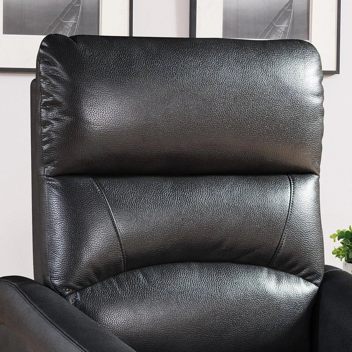 Black faux leather recliner chair in a room with framed pictures on the wall.
