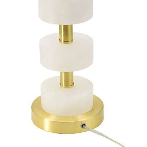 Table lamp with white marble-like accents and gold base  with cord on a white background