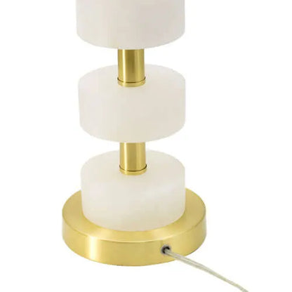 Table lamp with white marble-like accents and gold base  with cord on a white background
