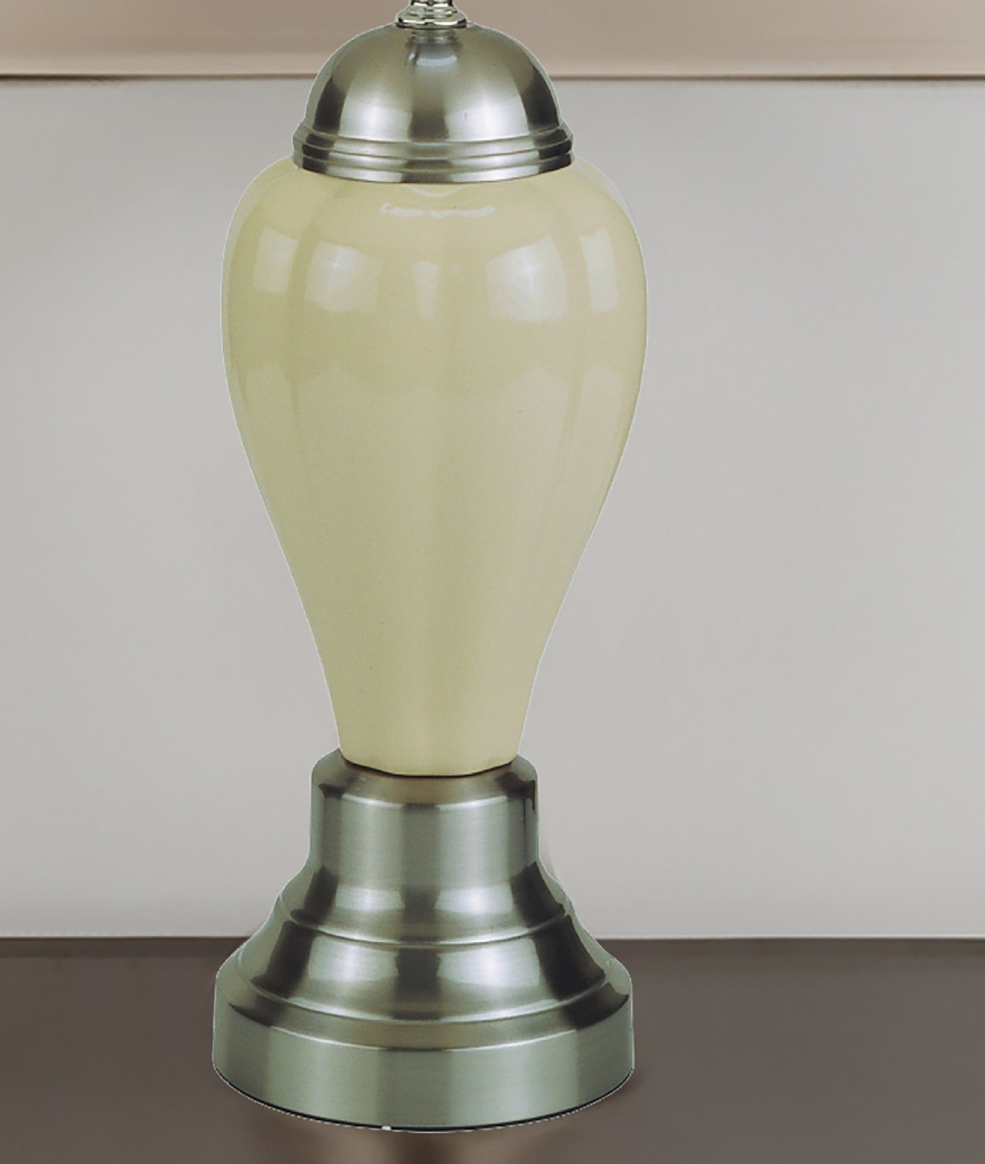 Decorative lamp with cream-colored ceramic base and silver metal top on a neutral background