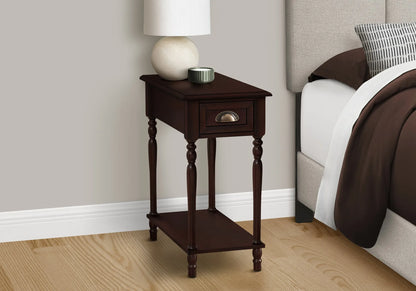 Wooden end table with a lamp and small container next to a bed with brown bedding.