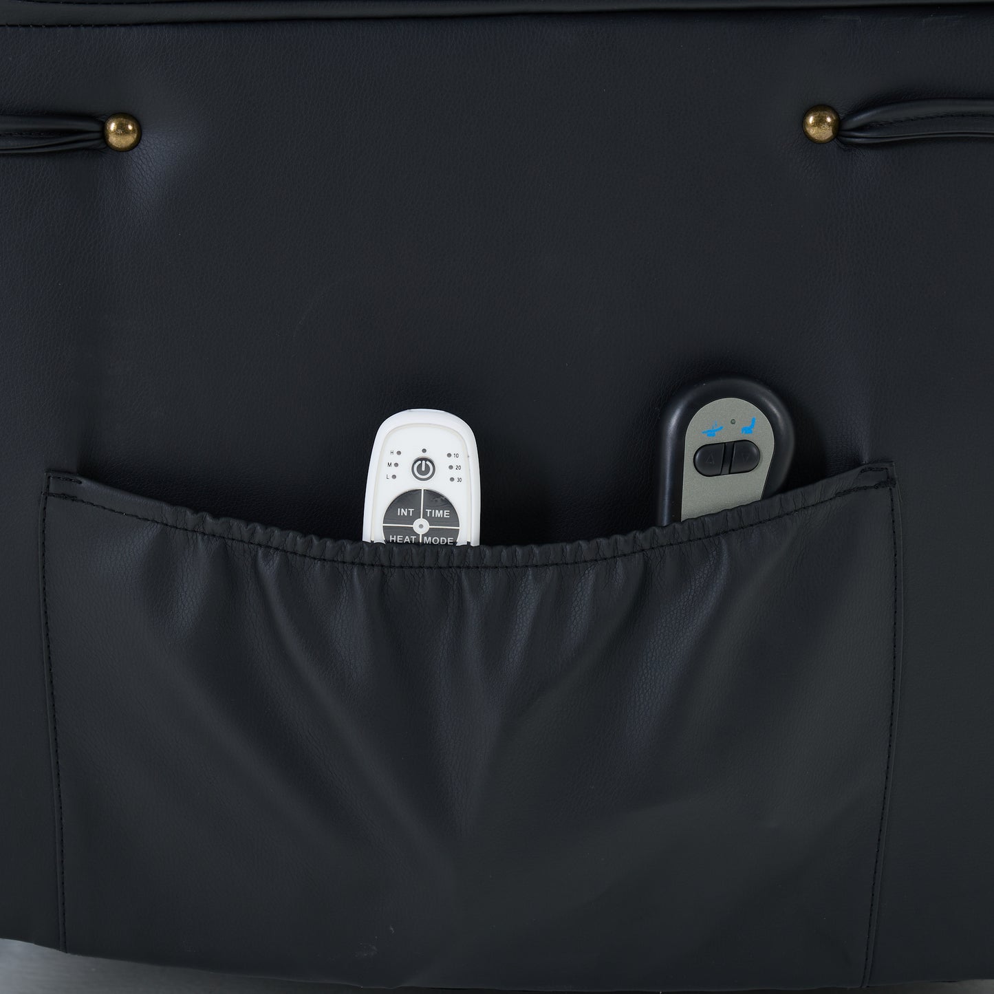 Black recliner chair storage pocket with  containing remote controls on a dark background