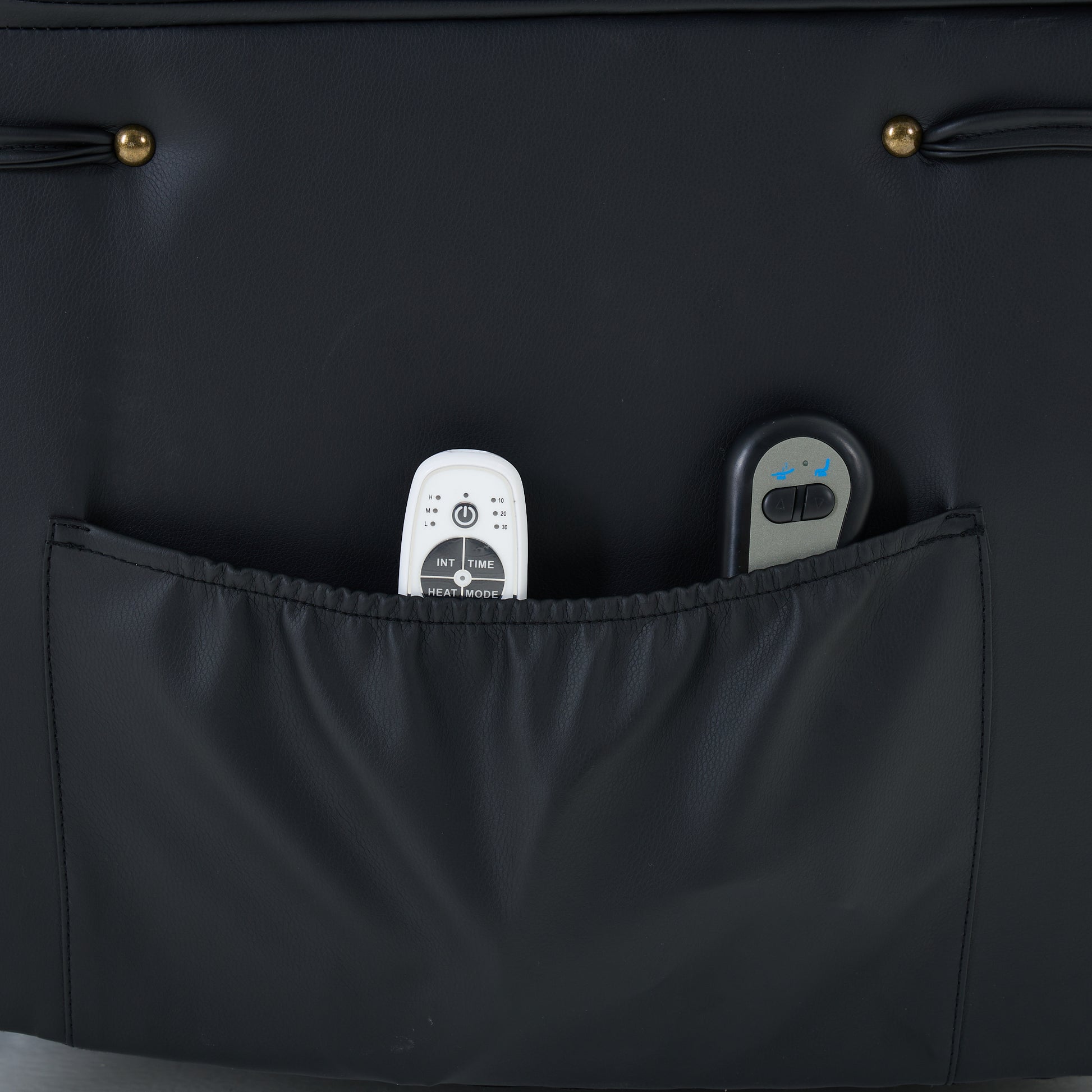 Black recliner chair storage pocket with  containing remote controls on a dark background