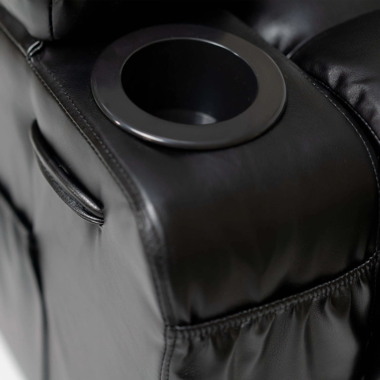 Close up of a cup holder on an overstuffed armrest of a black faux leather power lift recliner